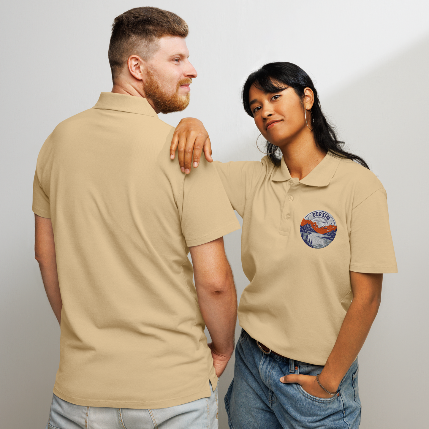 Unisex premium Polo Shirt sandfarben mit rundem Brustemblem